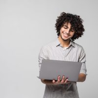 Side view portrait of a happy afro american man standing with laptop computer isolated on a white background